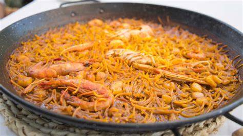 Playa de Gandía con un plato de fideuá en primer plano
