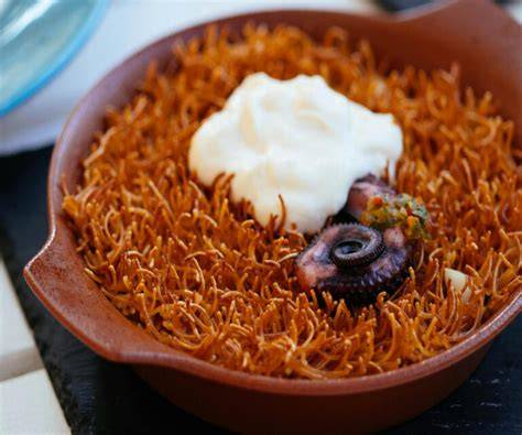 Plato de fideuá servido en paella con alioli al lado