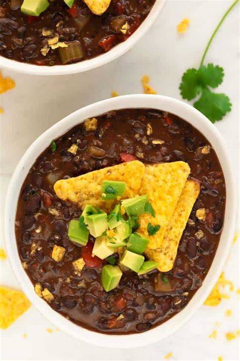 Sopa de alubias negras servida con aguacate y nachos