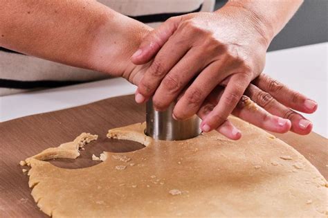 Manos cortando masa de galletas con un cortapastas