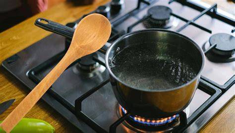 Polenta cocinándose en una cazuela, removiéndose con una cuchara de madera
